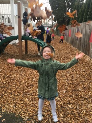 Preschooler throwing leaves on the playground