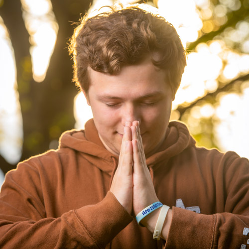 Male student with his hands together in prayer.