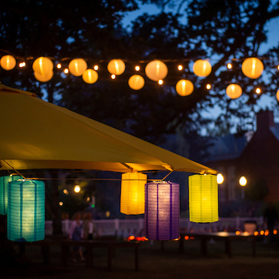 Strings of paper lanterns decorating outdoor event tents.