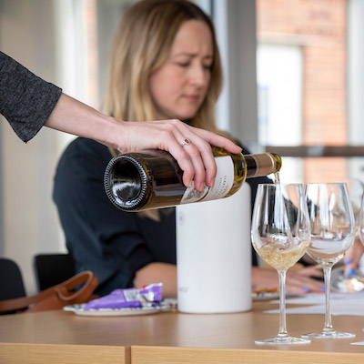 WSET instructor pouring a taste of wine for a student.