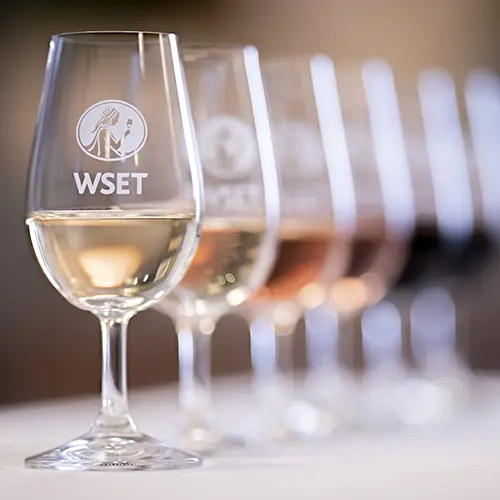 four wine glasses with the WSET logo etched on them.