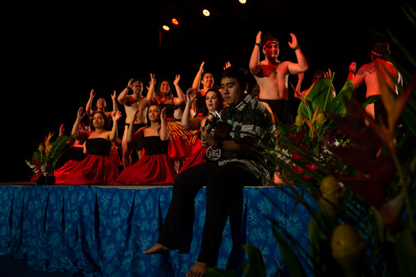Dancers on stage to performer playing ukulele