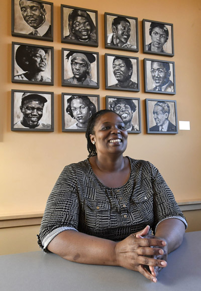 Angel sitting in the Corvallis-Albany NAACP office with portraits of Black historical figures behind her