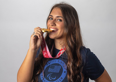 Annie Flood '25 biting her gold medal