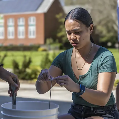 a student look at a dial while brewing outdoors.