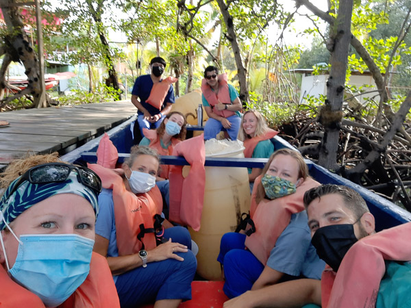 Cassandra smiling with seven fellow volunteers boarding a boat in life jackets