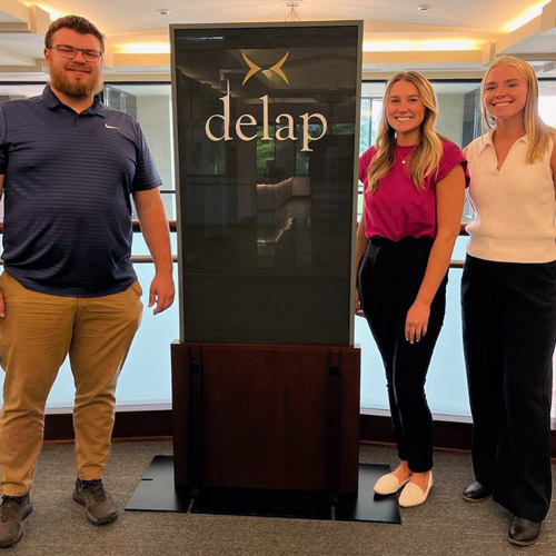 Nick Severson '24, Sophia vanderSommen ’25 and  Caitlin Hillman ’24 next to a Delap sign.