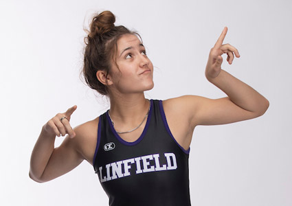 Hanna Gillas '26 posing with her arms flexed in her Linfield wrestling singlet