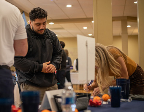 A student speaking to an employer at a Job Fair booth.