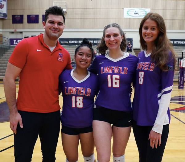 Kaden smiling for a photo with three volleyball players