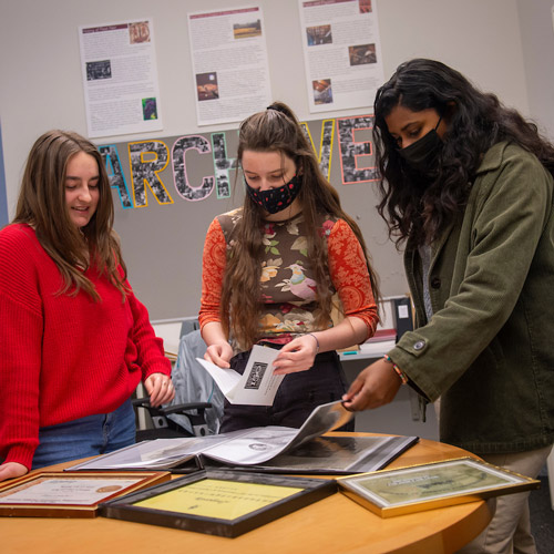 Three students studying a piece together in the archives
