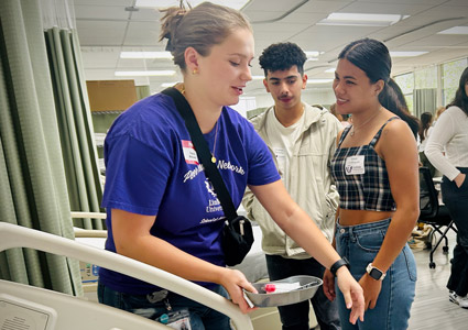 PRN advocate showing two new nursing students a manikin.