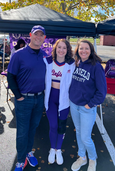 Olivia in her dance uniform with her parents, Joe and Stephanie, before the Fall Family Weekend football game