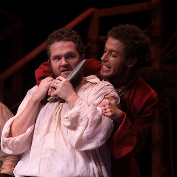 Robert Turner '24 in a scene from Treasure Island holding a prop knife to Killigrew the Kind's neck