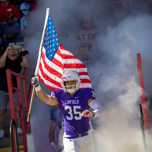 Tyler carrying the US flag onto the football field at Linfield's Sept. 11 2021 game
