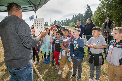 Linfield student teacher with elementary students studying insects at Miller Woods