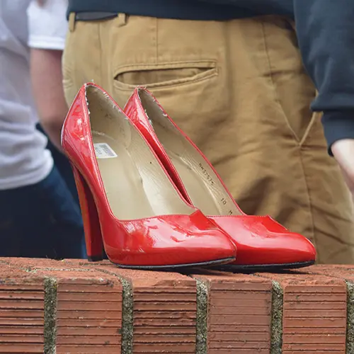 a pair of red heels on a brick wall.