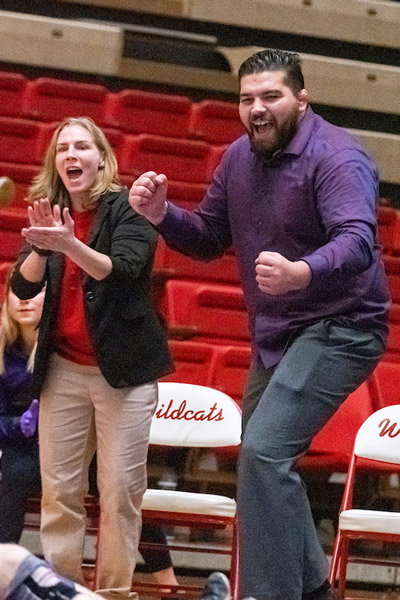 Coaches Alyssa Lampe and Chad Hanke cheering on a Linfield wrestler during a home match.