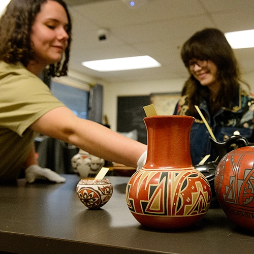 two students handling artifacts in the anthropology lab.