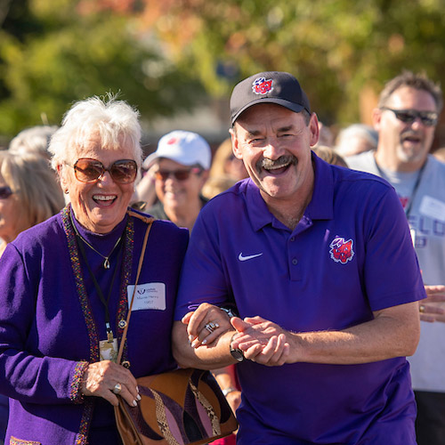 Linfield alumnus walking with Garry Killgore during a women in athletics celebration.