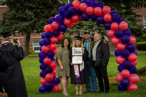 2021 graduate holding her diploma with three family members