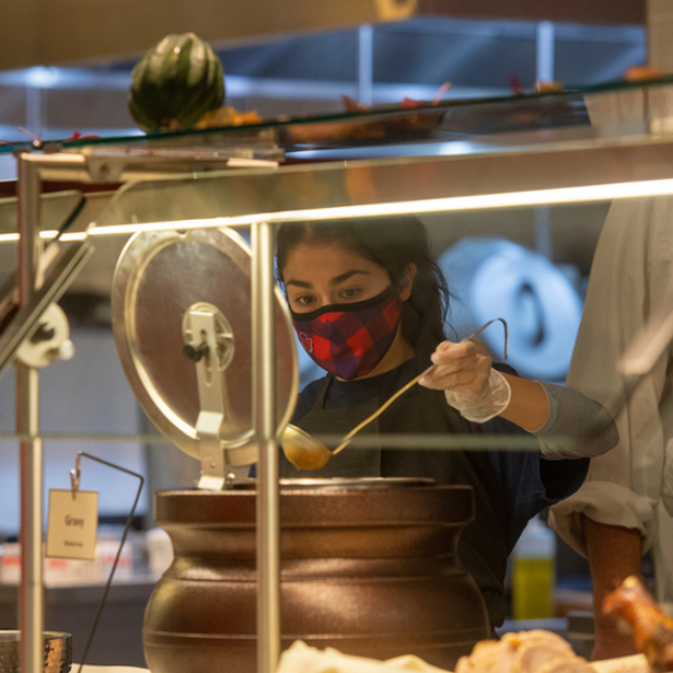 Student gets soup in dining hall wearing mask