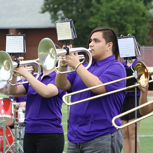 student playing a trumpet outdoors with the Wildcat band.