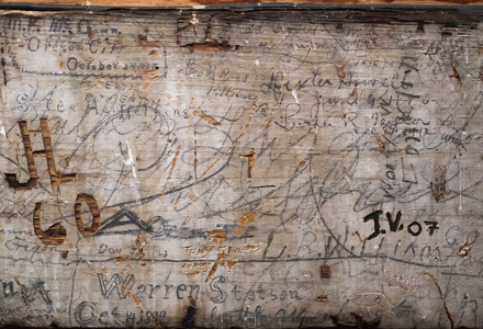 written initials on a wall in Pioneer Hall