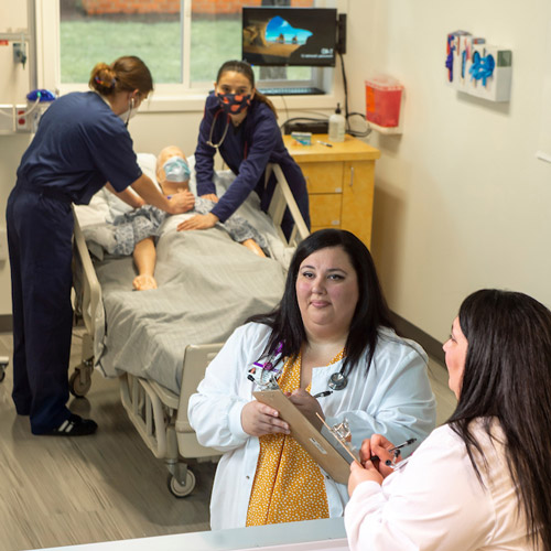 Nursing faculty member observing two nursing students in simulation lab