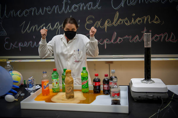 Chemistry lab coordinator demonstrating experiment for students.