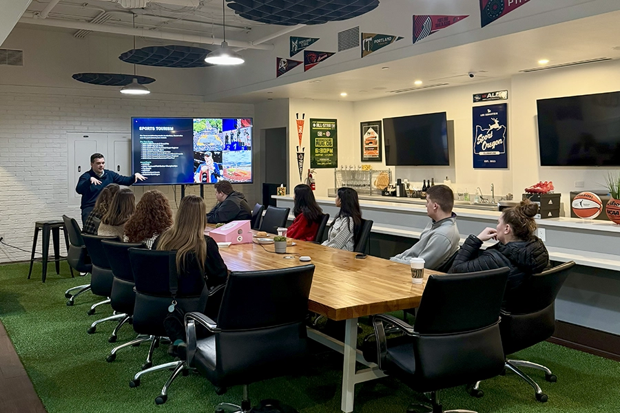Students from the Front Office Sports club sitting at a table at the offices of a professional sports team.