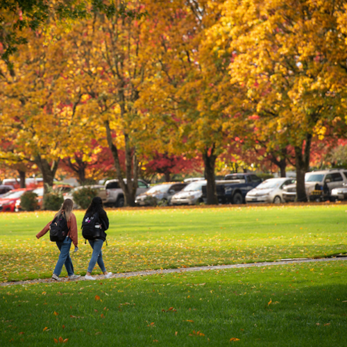Students walk in front of a parking lot on McMinnville campus