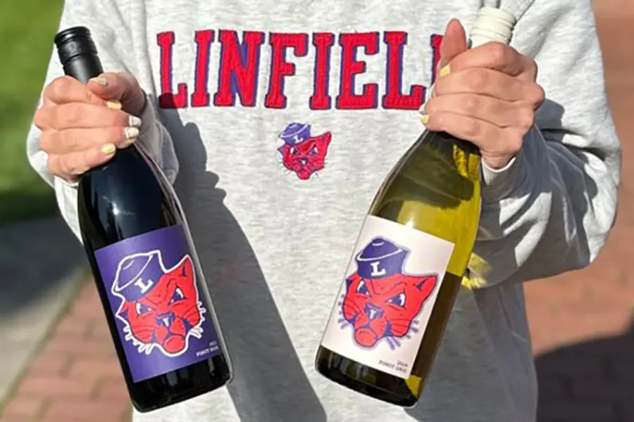 a student holding two bottles of wine with the new labels.