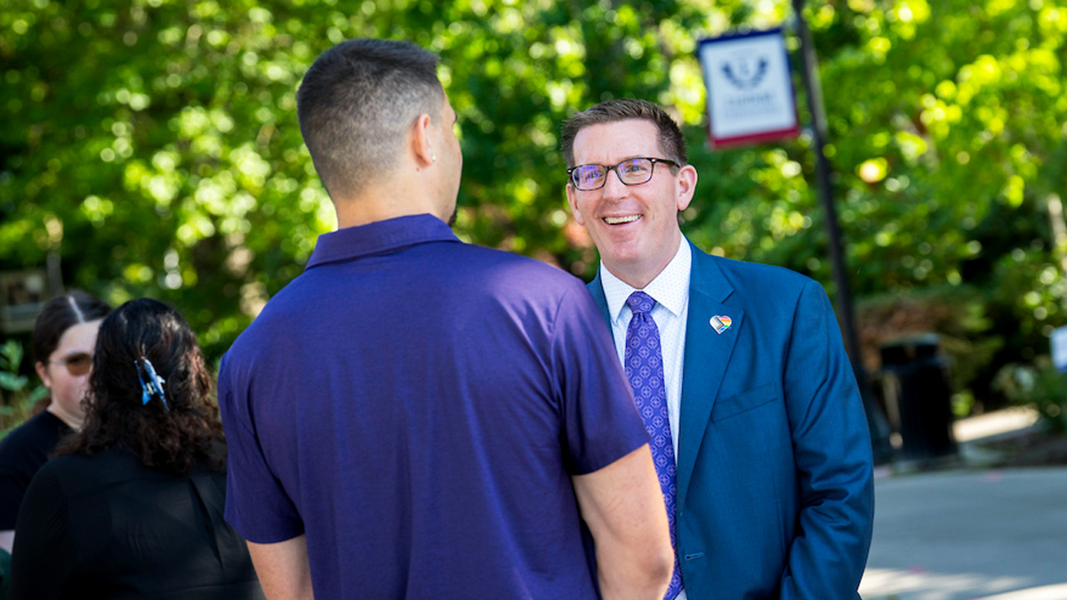 Mark Blegen speaks to a person outside on campus