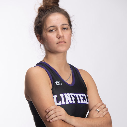 Hanna Gillas '26 in her Linfield wrestling singlet posing with her arms crossed