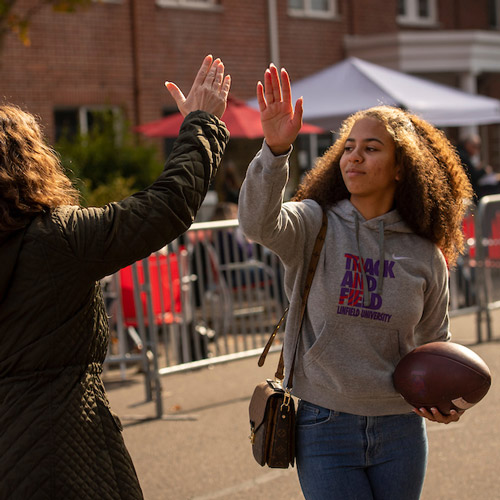 two students high-fiving before a football game