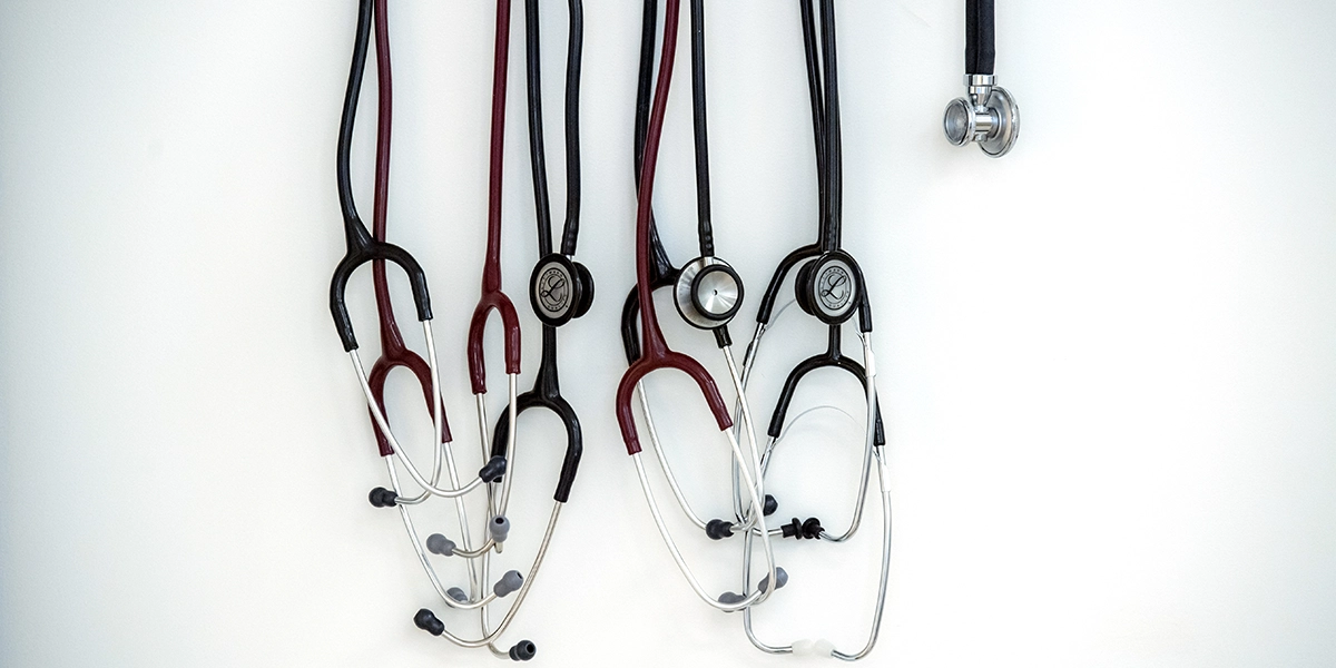 Four stethoscopes handing in front of a white wall.