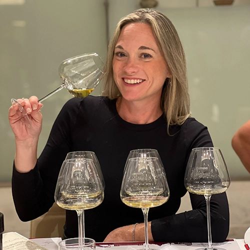 Photo of Kristie Wenz holding a wine glass and a bottle of wine.