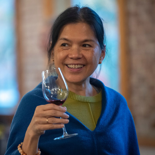 A member of the Oak and Vine Society smiling with a glass of wine in her hand