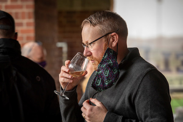 A male Oak and Vine member smelling his glass of white wine